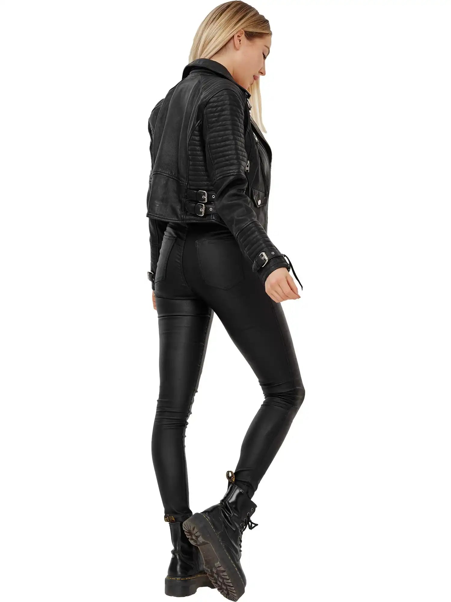 Eine Frau mit langen blonden Haaren trägt die trueprodigy Freya Bikerlederjacke mit Schnallen, schwarzer Hose und Stiefeln und steht leicht zur Seite vor einem weißen Hintergrund für einen coolen Biker-Look.