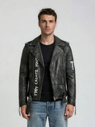 Ein Mann trägt die trueprodigy Biker Lederjacke Herren "Russell" mit Rücken-Print, dazu ein schwarzes T-Shirt und blaue Jeans, und steht vor einem schlichten, hellen Hintergrund.