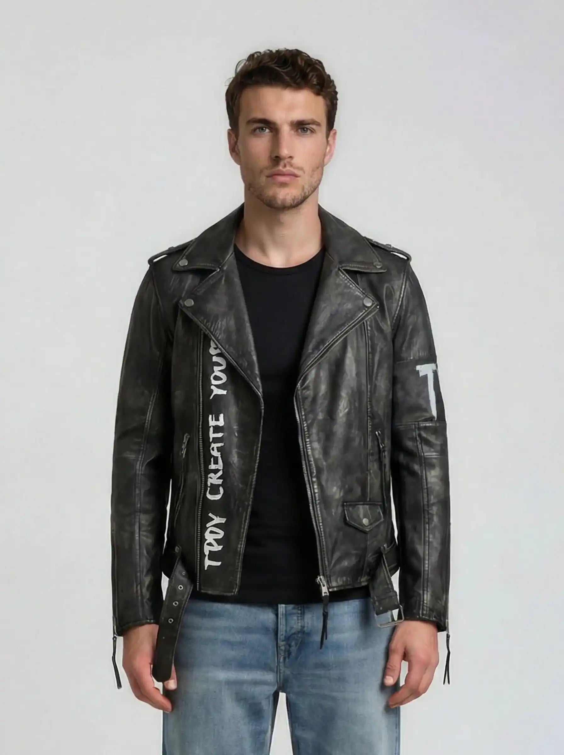 Ein Mann trägt die trueprodigy Biker Lederjacke Herren "Russell" mit Rücken-Print, dazu ein schwarzes T-Shirt und blaue Jeans, und steht vor einem schlichten, hellen Hintergrund.