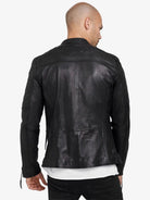 Von hinten ist eine Person mit rasiertem Kopf zu sehen, die eine schwarze Franky Lederjacke mit Stehkragen von trueprodigy mit gesteppten Ärmeln und Schultern, dem eingeprägten Markennamen auf dem oberen Rücken, und einem weißen Hemd darunter trägt.