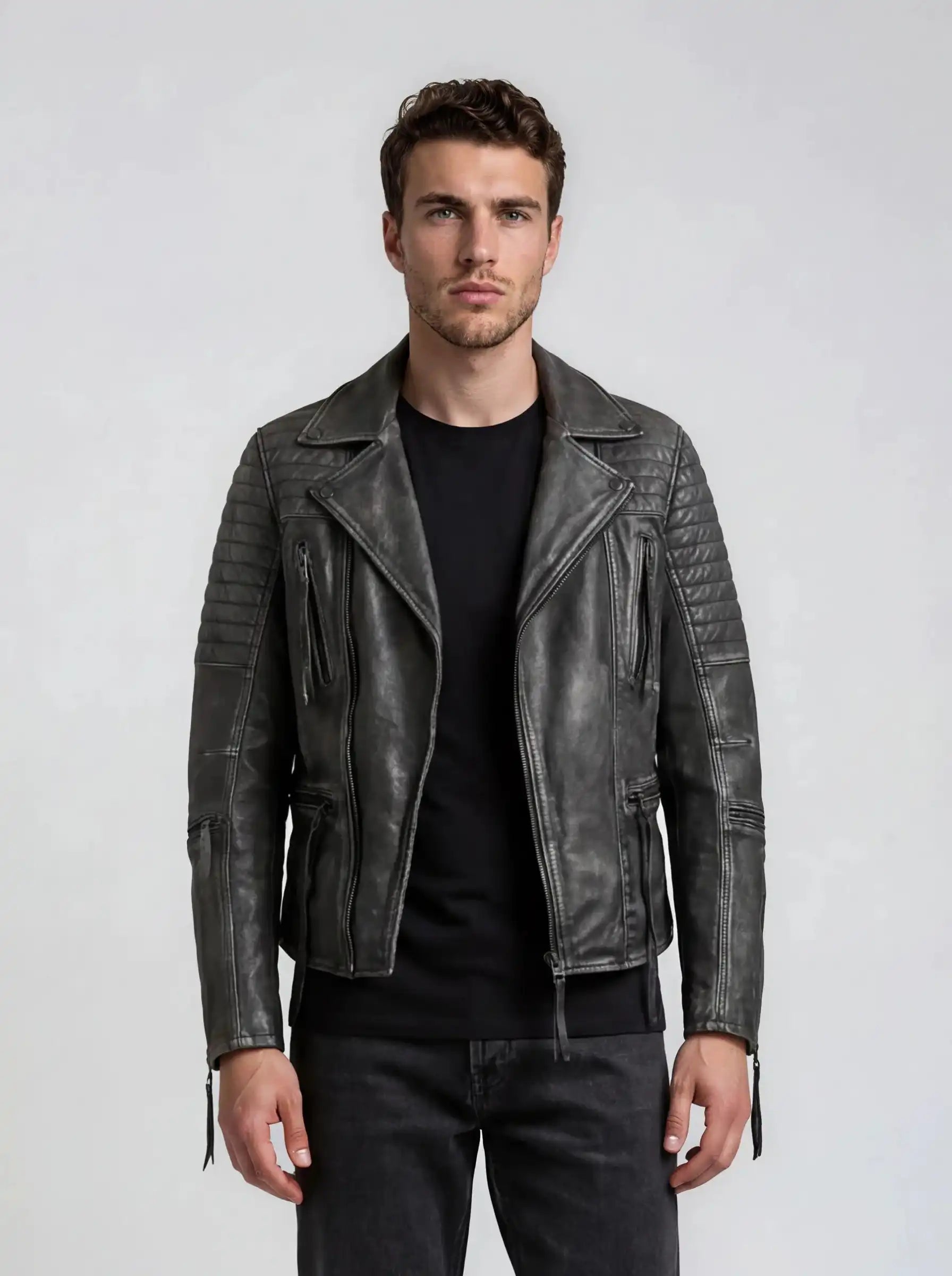 Ein Mann mit kurzen braunen Haaren trägt die Vintage Biker Lederjacke Herren "Bryan" mit Steppung von trueprodigy über einem schwarzen T-Shirt und dunklen Jeans, steht vor hellem Hintergrund und blickt neutral nach vorn.