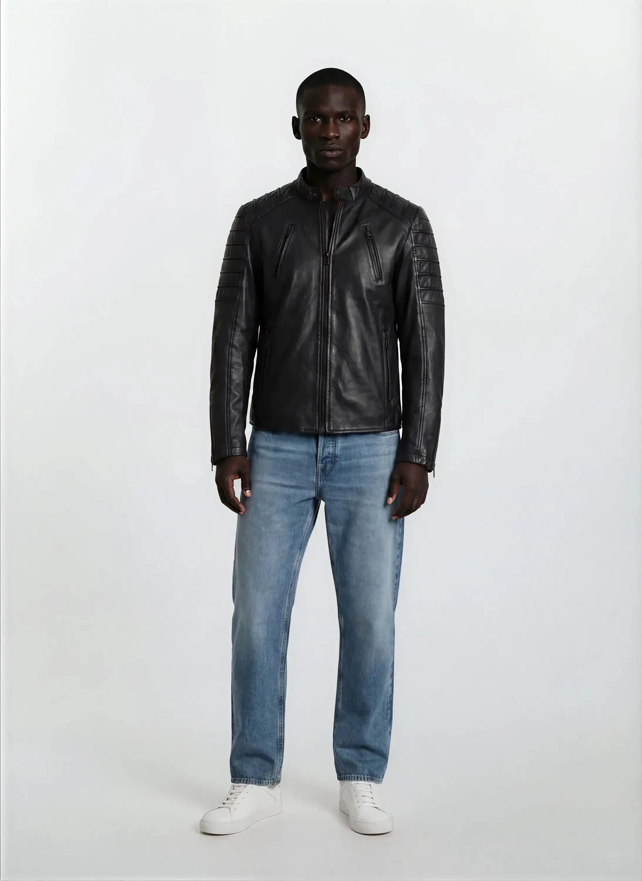 Eine Person steht mit dem Gesicht nach vorne vor einem schlichten weißen Hintergrund und trägt eine trueprodigy Slim-Fit-Lederjacke mit Stehkragen & Zipper-Details, hellblaue Jeans und weiße Turnschuhe.