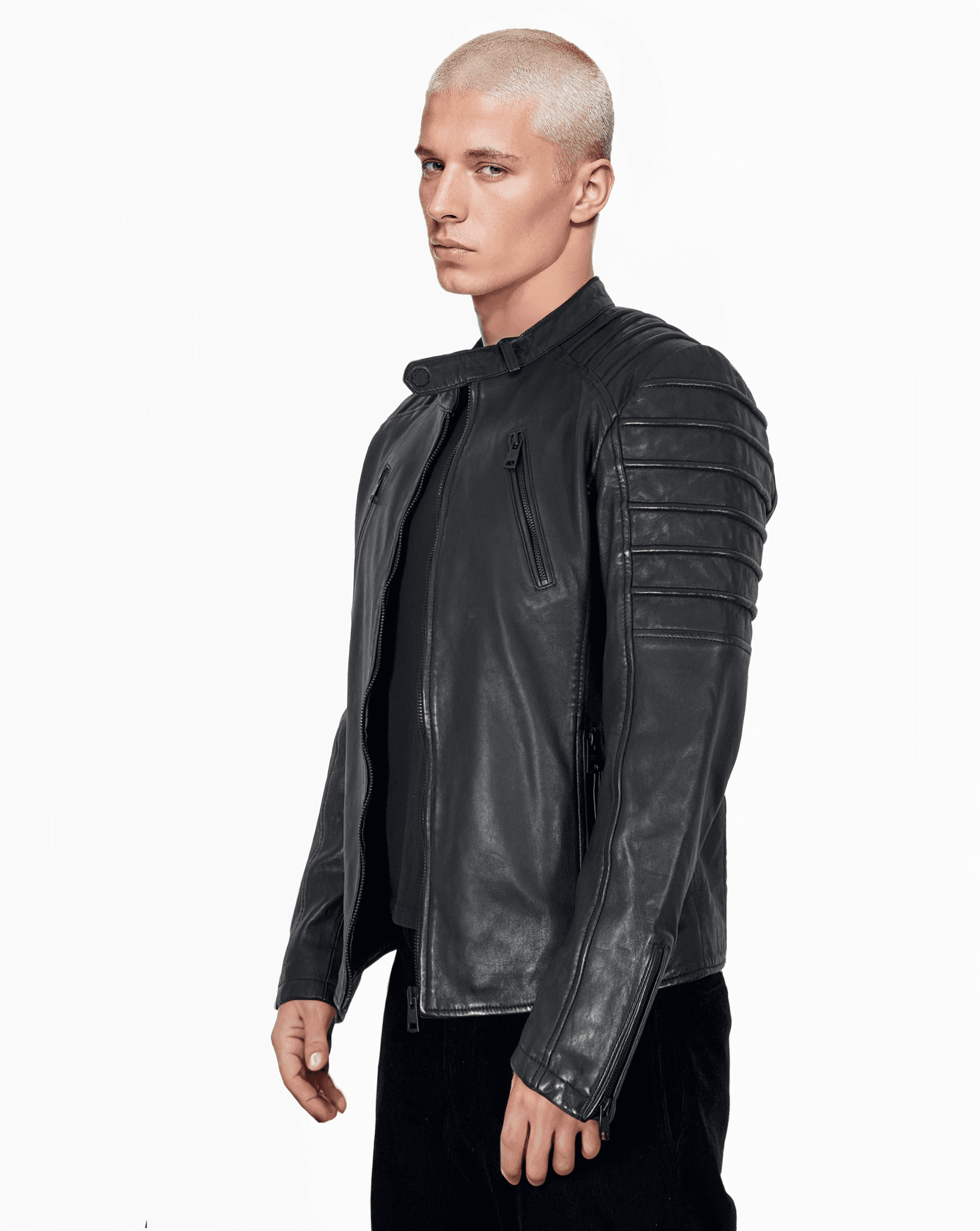 Eine Person trägt eine trueprodigy Dash Lederjacke aus Schafsleder mit gesteppten Schultern und Stehkragen, dazu ein schwarzes Hemd. Sie hat kurzes, helles Haar vor einem schlichten weißen Hintergrund.