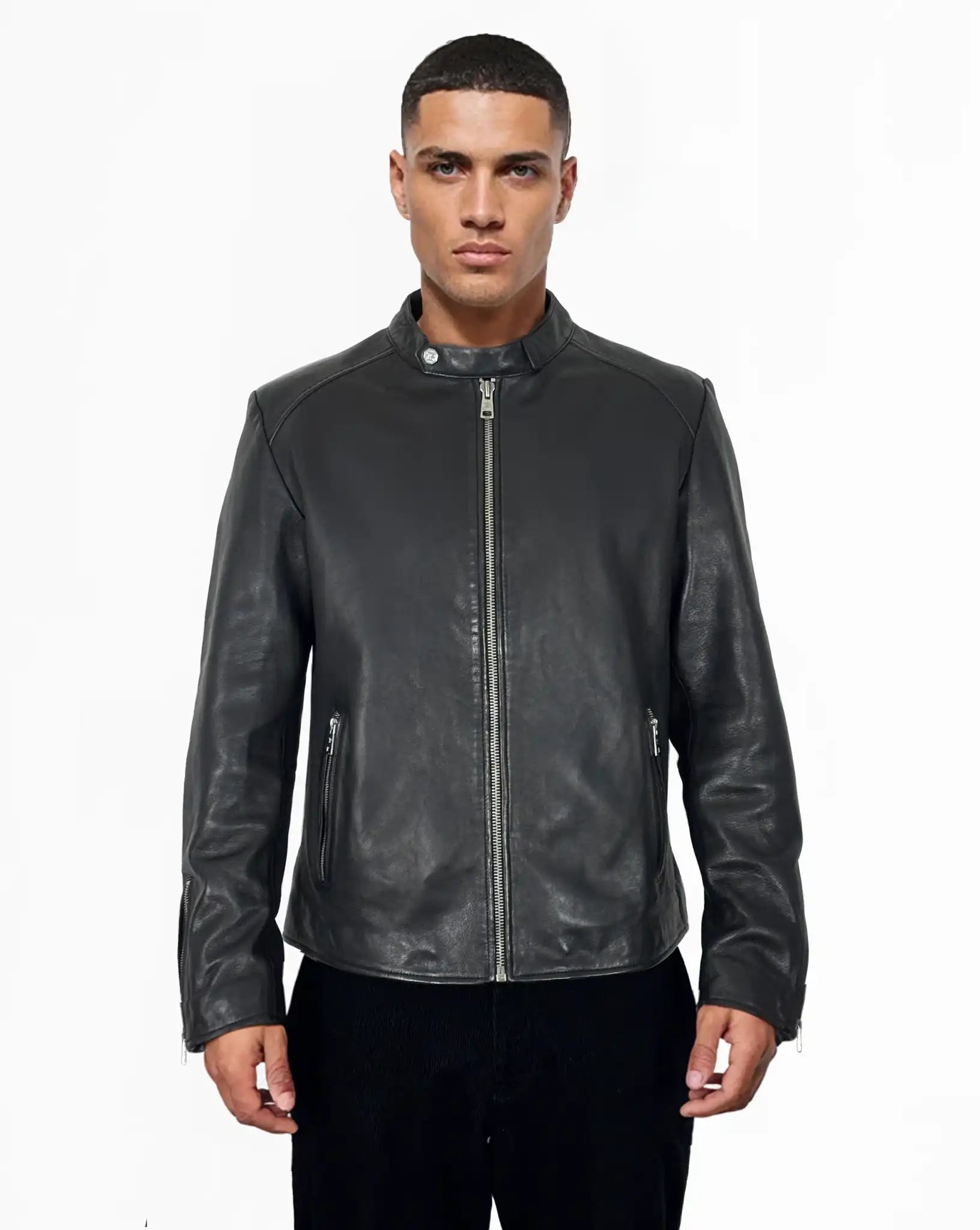 Eine Person steht vor der Kamera und trägt die trueprodigy Jonas Slim-Fit-Lederjacke mit sichtbarem 3D-Rückenlogo mit Frontreißverschluss und Reißverschlusstaschen, gepaart mit einer schwarzen Hose, vor einem schlichten weißen Hintergrund.