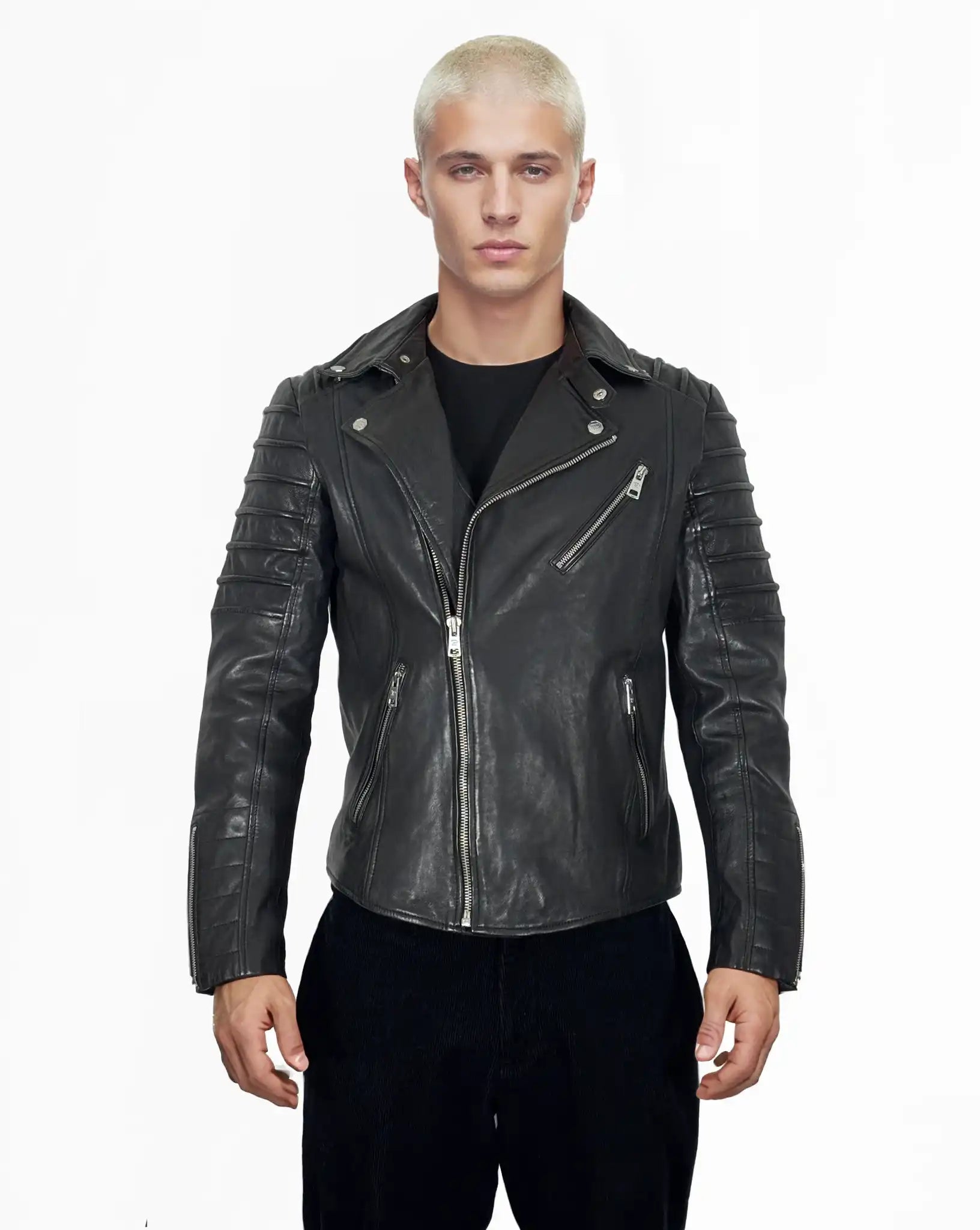 Eine Person mit kurzen, gebleichten blonden Haaren blickt nach vorne, trägt die Jacke John von trueprodigy über einem schwarzen Hemd und einer schwarzen Hose und steht vor einem schlichten weißen Hintergrund.