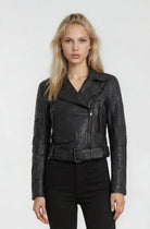 Eine Frau mit langen blonden Haaren trägt die Bikerlederjacke mit Ösen von trueprodigy aus Schafsleder vor schlicht hellgrauem Hintergrund.