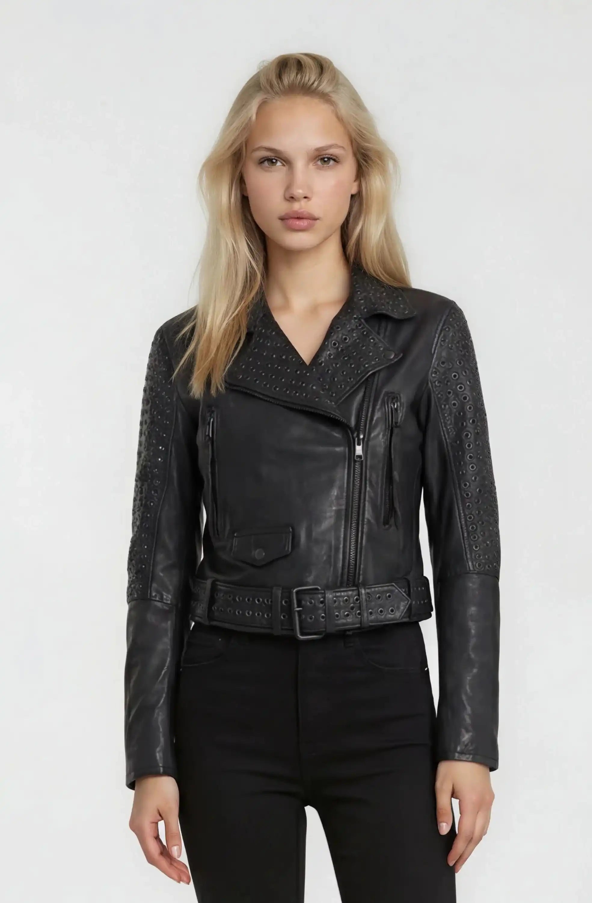 Eine Frau mit langen blonden Haaren trägt die Bikerlederjacke mit Ösen von trueprodigy aus Schafsleder vor schlicht hellgrauem Hintergrund.