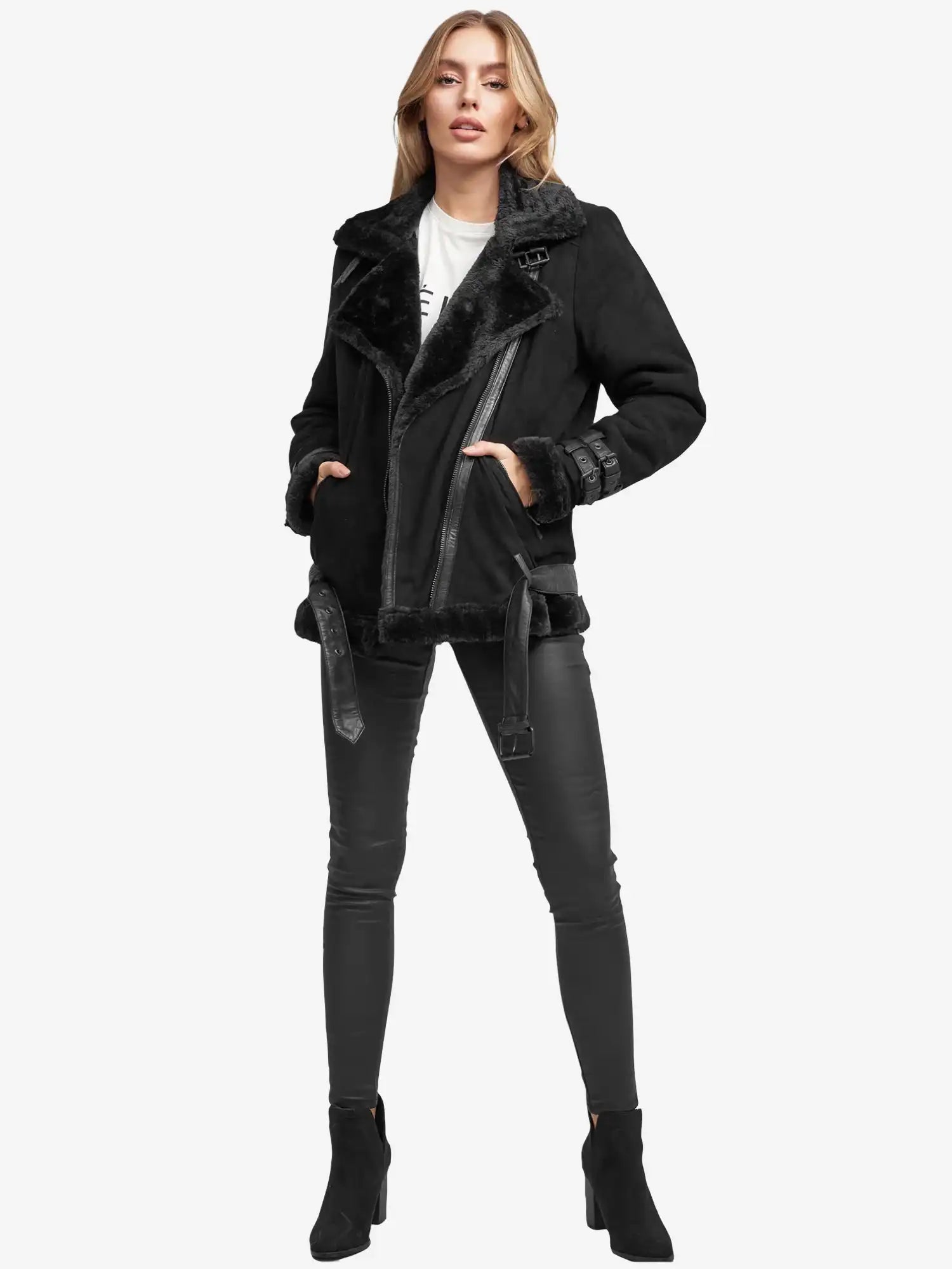 Eine Person steht vor der Kamera und trägt eine echte Aloy Wilderlederjacke mit Gürtel, eine schwarze Hose in Lederoptik, schwarze Stiefeletten und darunter ein weißes Oberteil. Der Hintergrund ist einfarbig weiß.