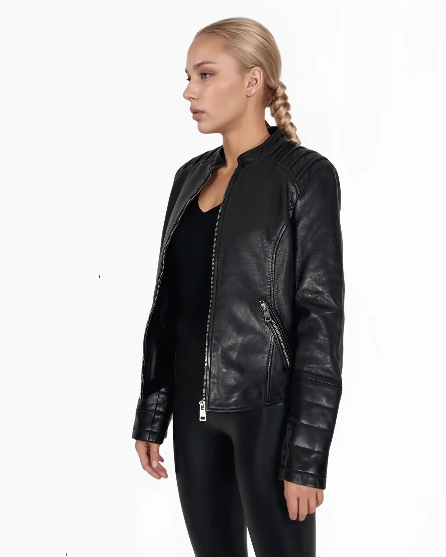Eine blonde Frau mit einem Zopf trägt die Trueprodigy Raegan taillierte Lederjacke mit Stehkragen, Steppnähten & silbernen Reißverschlüssen und schwarze Hosen, stehend vor einem schlichten weißen Hintergrund, leicht nach links gewandt.
