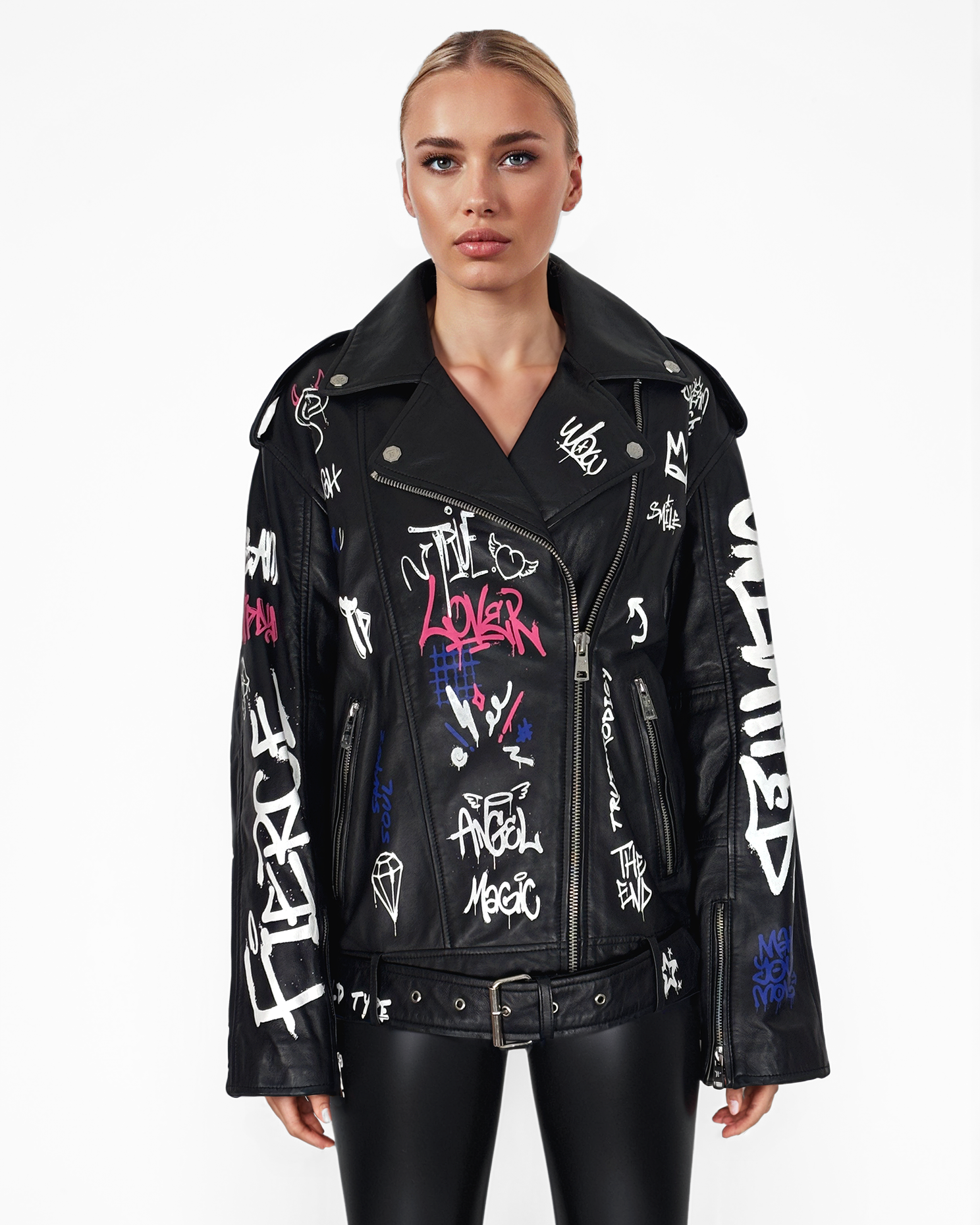 Eine Frau blickt nach vorne und trägt die schwarze Graffiti-Lederjacke Anya von trueprodigy mit weißen und bunten Texten und Zeichnungen im Graffiti-Stil, kombiniert mit schwarzen Hosen auf einem schlichten weißen Hintergrund.