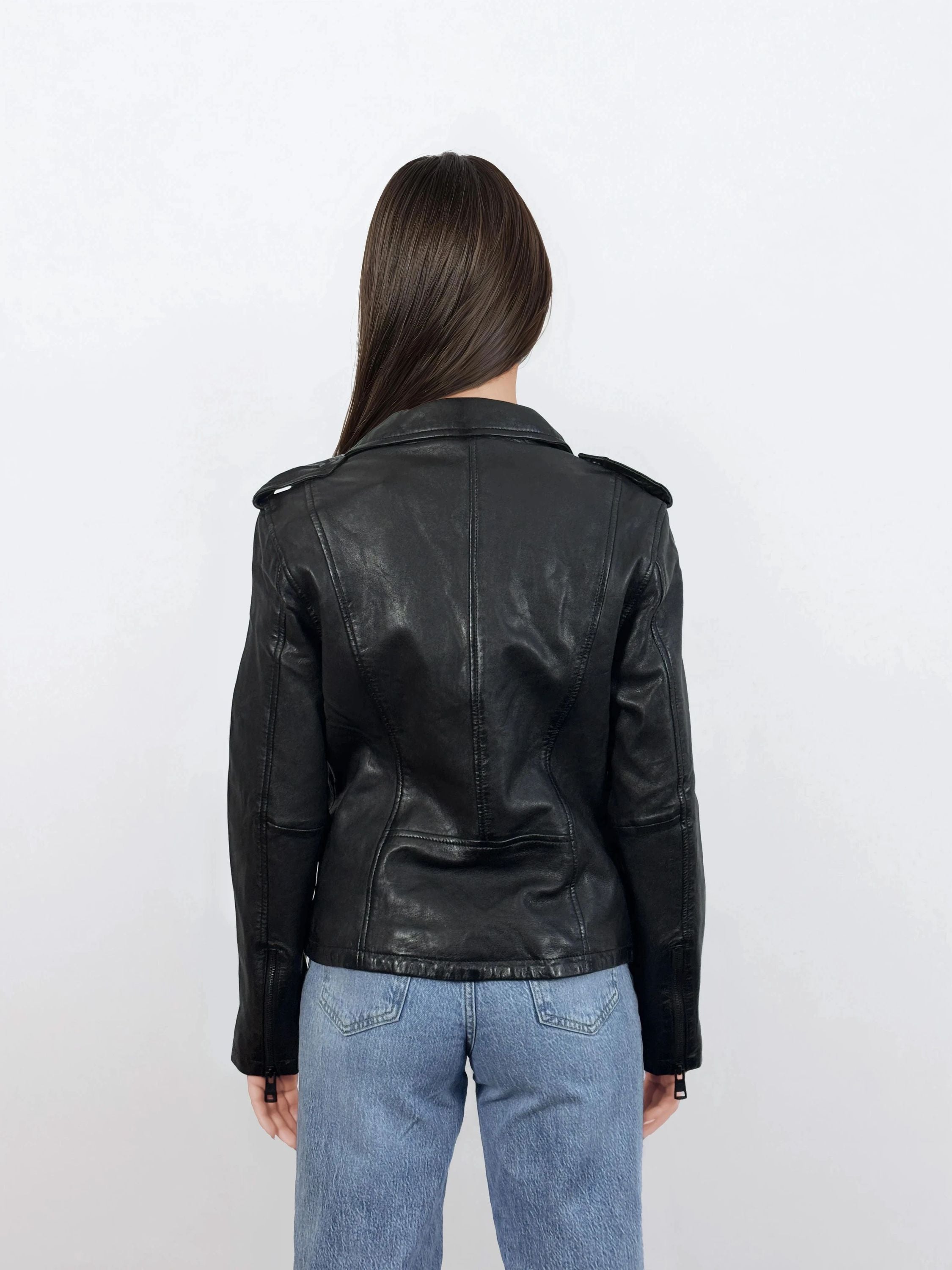 Eine Person mit glattem braunem Haar trägt eine trueprodigy Damen Lederjacke aus Schafsleder in Schwarz im klassischen Biker-Stil und Blue Jeans und steht mit dem Rücken zur Kamera vor einem schlichten weißen Hintergrund.