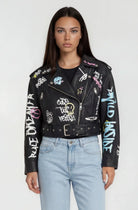 Eine Person mit glattem dunklem Haar trägt die trueprodigy Oversize Lederjacke mit Grafittiprint und Gürtel, gestylt mit hellblauen High-Waisted Jeans, vor einem schlichten hellen Hintergrund.