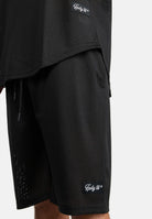 Nahaufnahme einer Person, die die Allen Short aus Mesh und das dazu passende schwarze Mesh-Top von trueprodigy trägt, beide mit kleinen rechteckigen Markenetiketten an den Säumen. Der Hintergrund ist einfarbig weiß.