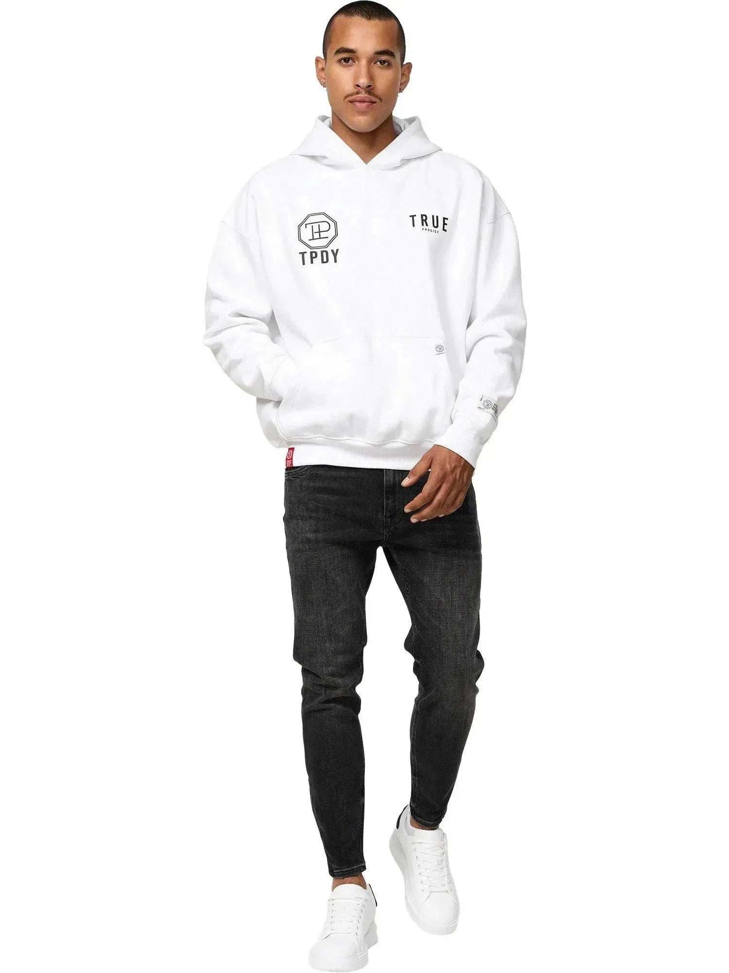 Eine Person präsentiert selbstbewusst den Trueprodigy Aaren Oversized Hoodie mit Print, mit schwarzen „TPDY“-Buchstaben und Logos auf Weiß. Sie kombiniert ihn mit schwarzen Jeans und weißen Sneakers und posiert vor einem schlichten weißen Hintergrund für dieses stylische Unisex-Ensemble.