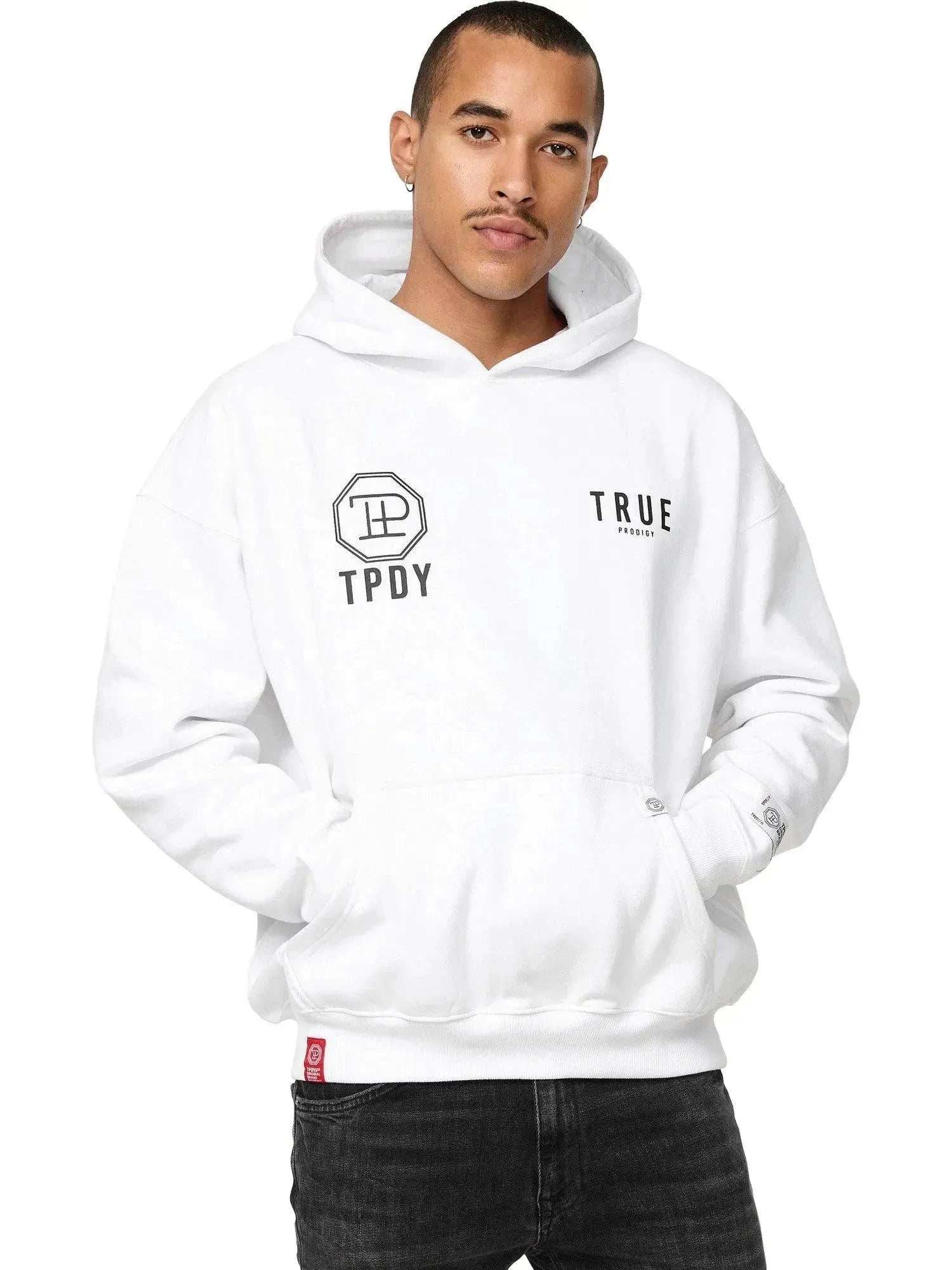 Eine Person mit kurzen Haaren trägt einen Trueprodigy Aaren Oversized Hoodie mit Print in Weiß mit schwarzen Symbolen, „TPDY“ und Logos sowie einer Fronttasche vor einem weißen Hintergrund.