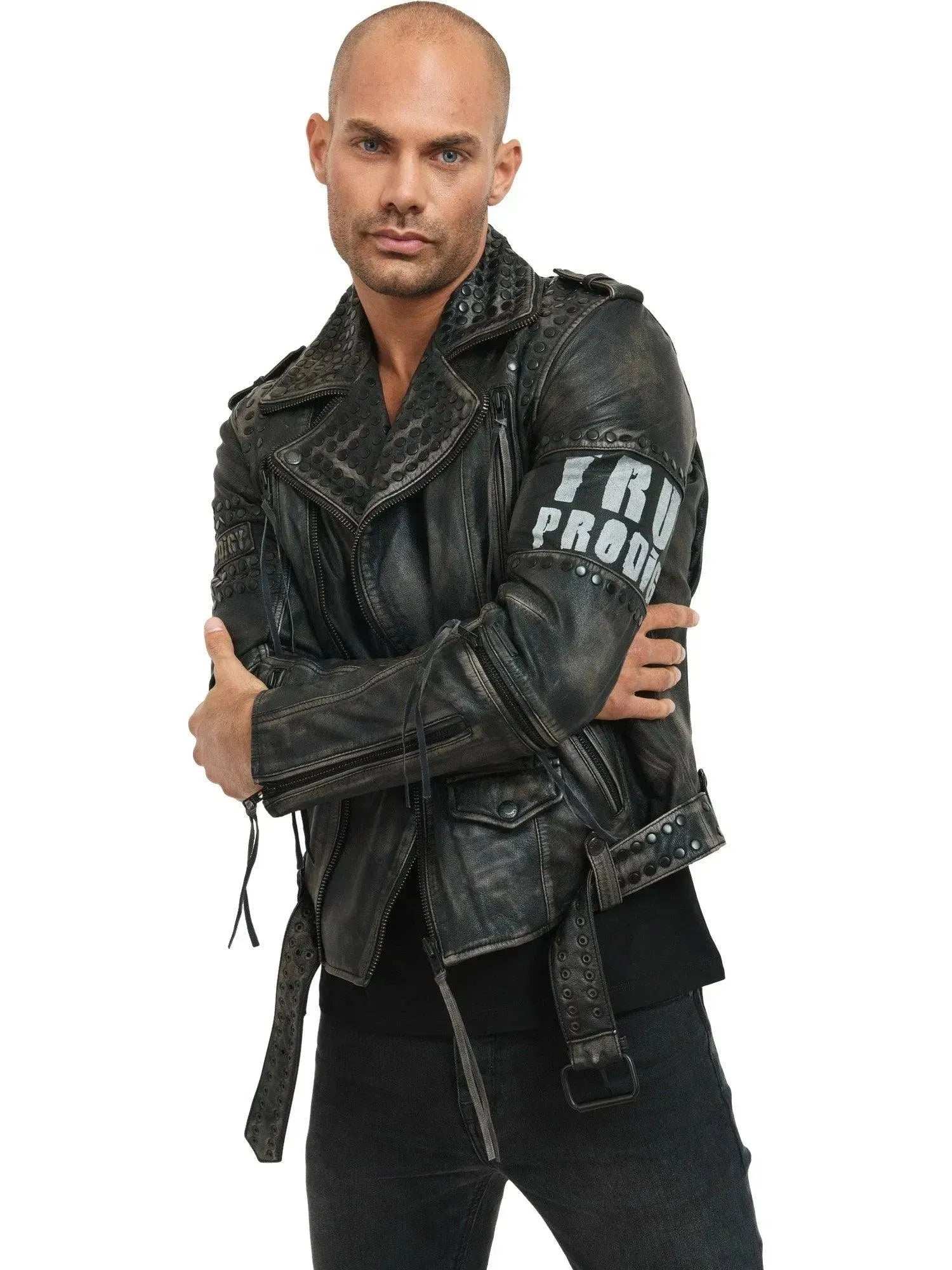 Eine Person, die die trueprodigy Dwayne Lederjacke mit Nieten und Druck im kantigen Biker-Look mit „PRODIGE“ auf dem Ärmel trägt, steht selbstbewusst mit verschränkten Armen vor einem weißen Hintergrund.