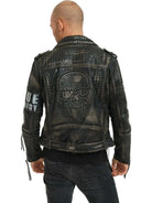 Ein kahlköpfiger Mann präsentiert trueprodigys Dwayne Lederjacke mit Nieten und Druck, die auf der Rückseite ein Totenkopf-Emblem trägt. Auf einem Ärmel der Jacke steht „TRUE“ und an den Manschetten sind Schnürsenkel. Er trägt dazu eine schwarze Hose für den ultimativen Biker-Look, während er von der Kamera abgewandt ist.