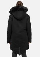 Eine Person mit geflochtenem Haar trägt einen trueprodigy Harvey F Damenparka mit Kapuze und Kunstfell, einen langen schwarzen Winterparka. Der Mantel hat einen Schlitz mit Reißverschluss auf der Rückseite und gesteppte Ärmel, was seine Länge und Designdetails von hinten betont.