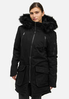 Eine Person trägt den schwarzen Damenparka Harvey F von trueprodigy mit Kapuze und Kunstfell, einen Wintermantel mit Kapuze, Frontreißverschluss, Pattentaschen und Brusttaschen mit Reißverschluss. Die Kapuze ist hochgezogen, während sie vor einem schlichten weißen Hintergrund steht.