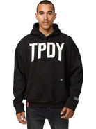Vor einem schlichten weißen Hintergrund steht jemand im Trueprodigy Janne Oversized Hoodie mit Print – mit „TPDY“ in Weiß – stilvoll da. Die kurzen Haare und der neutrale Ausdruck verstärken die allgemeine Coolness dieses Unisex-Kapuzensweatshirts.