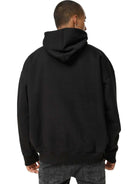 Jemand, der einen schwarzen Janne Oversized Hoodie mit Print und dunkle Jeans trägt, ist von hinten zu sehen, mit heruntergelassener Kapuze, wodurch das Trueprodigy-Logo dezent vor einem weißen Hintergrund zu sehen ist.