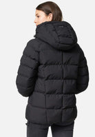 Vor einem schlichten weißen Hintergrund trägt eine Person mit braunem Haar, die von der Kamera abgewandt ist, graue Hosen und die trueprodigy Murphy F Matte Steppjacke mit Kapuze. Das schwarze wasserabweisende Material der Jacke verleiht sowohl Stil als auch Funktionalität.