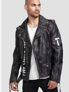 Eine Person trägt die Russell Lederjacke mit Print von trueprodigy, mit Nieten, silbernen Reißverschlüssen und sichtbaren Nähten für einen klassischen Biker-Look. Das Ensemble besteht aus einem weißen T-Shirt und einer schwarzen Hose vor einem schlichten hellgrauen Hintergrund.