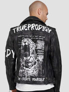 Ein kahlköpfiger Mann trägt die Lederjacke „Russell“ von TrueProdigy im Biker-Look mit weißem Text und grafischem Aufdruck eines brüllenden Leoparden auf dem Rücken. Sie hat ein Distressed-Design auf einem schlichten grauen Hintergrund mit auffälligem Aufdruck „TRUEPRODIGY“.